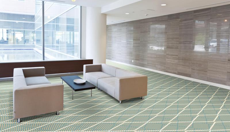 Geometric QuickWeave Brintons carpet in soft grey and cream tones with sofa and table in reception area